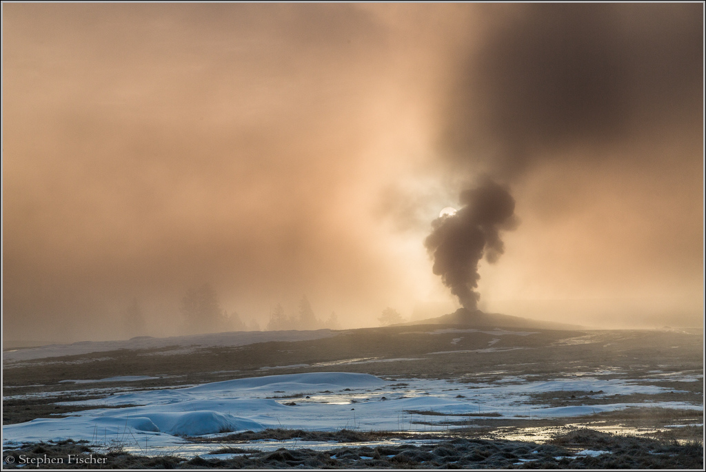 Old Faithful as silhouetted by sunrise